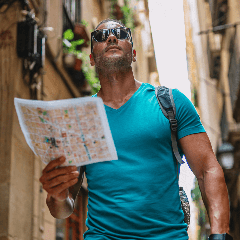 Image of a man holding a map walking through a foreign city.