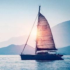 Image of a sailboat gliding across the water with billowing sails.