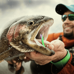 Image of a fisherman holding a large fish with a hook in it’s mouth.