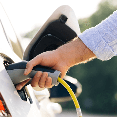 Image of a person charging an electric vehicle at a charging station.